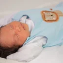 Baby slaapt op de rug in een baby slaapzak in het ledikantje