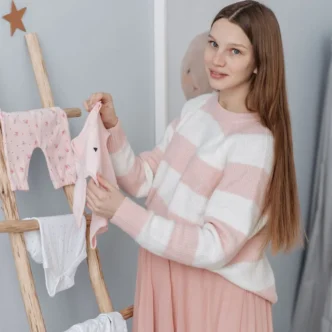 Zwangere vrouw legt babykleding klaar volgens haar baby uitzetlijst