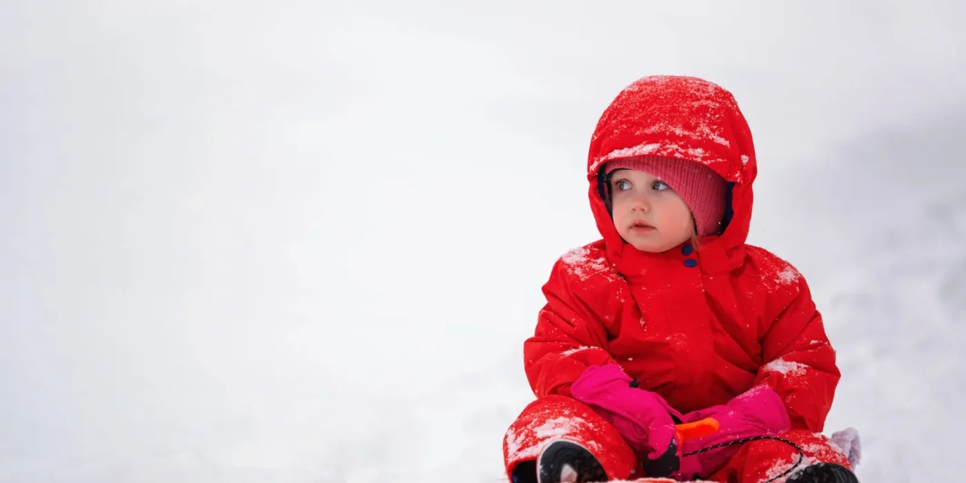 Baby in een warme winterjas met capuchon buiten in de kou