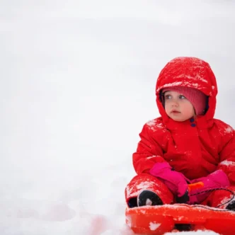 Baby in een warme winterjas met capuchon buiten in de kou