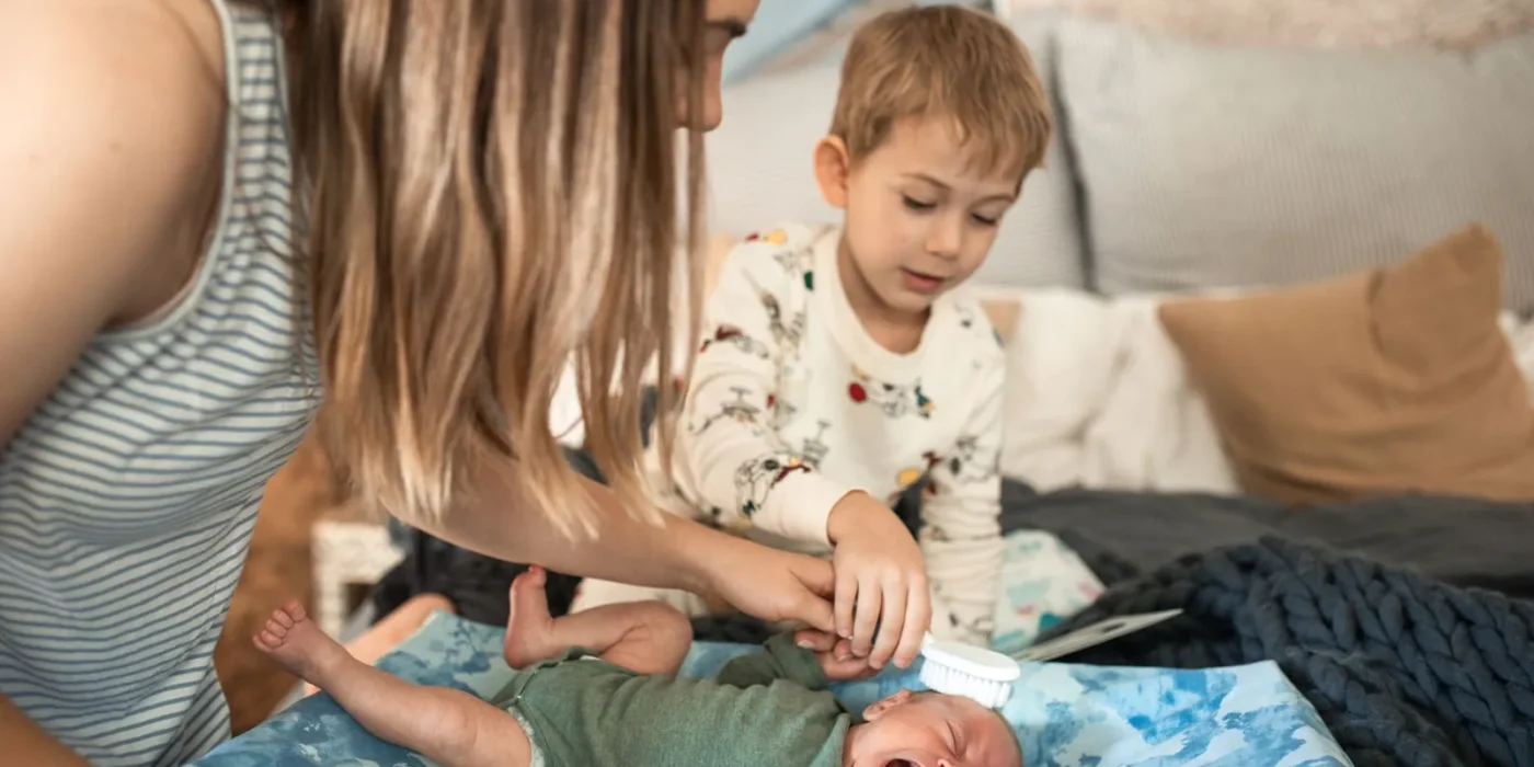 Ouder borstelt voorzichtig het hoofdje van een baby met berg
