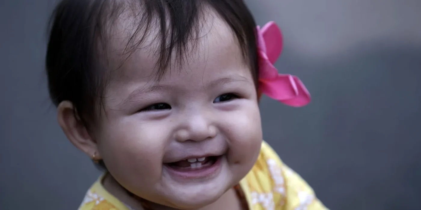 Lachende baby met de eerste tandjes bijt op een bijtring