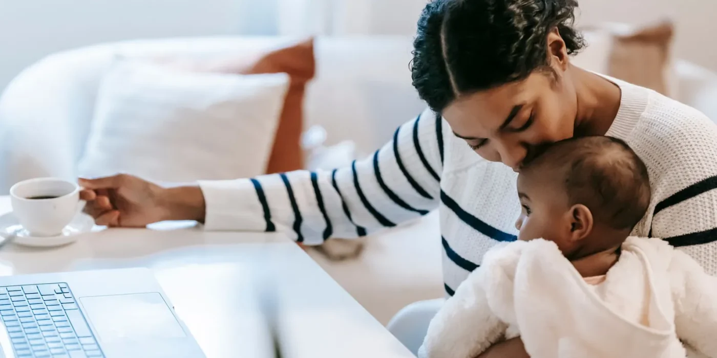 Baby drinkt water uit een klein open bekertje met hulp van een ouder